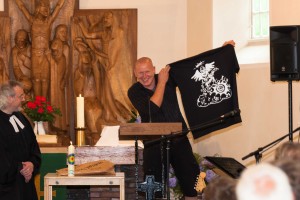 B-Engels! Wolfgang Machholz freute sich besonders über das Abschiedsshirt, das von Bandmitglied Jan Bülck eigens für ihn gestaltet und ihm von Pastor Erich Faehling überreicht wurde.