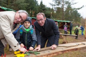 Einmal Schleife bitte! "Die Miniwaldweihnacht für Grundschulen ist schon eine ganz besondere Idee und ein tolles Geschenk für die Kinder", fanden Dr. Stephan Kronberg Links) und Kai Gräper aus dem Vorstand der Stiftung der Sparkasse Südholstein beim Holzsteckenbasteln mit Adrian (7) aus Bad Bramstedt. 